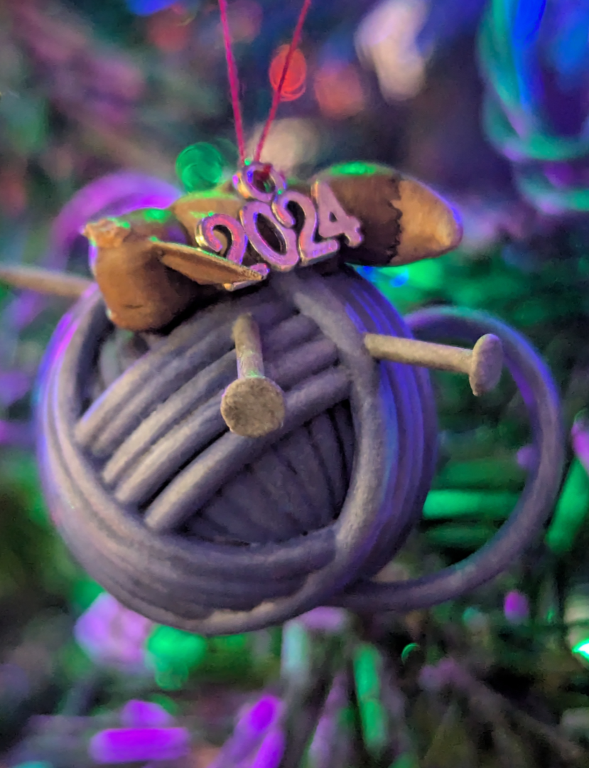 Christmas ornament featuring a small Eevee asleep on a ball of yarn. Hand painted