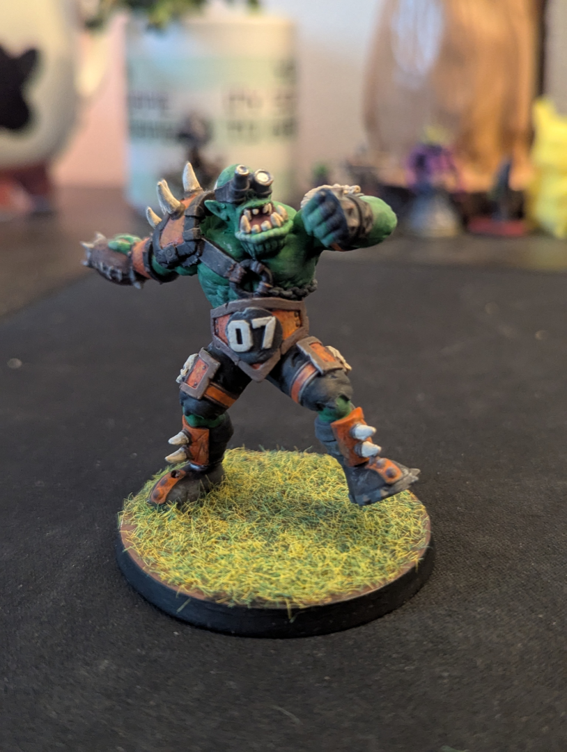 A hand painted orc in orange and brown armor throwing a football